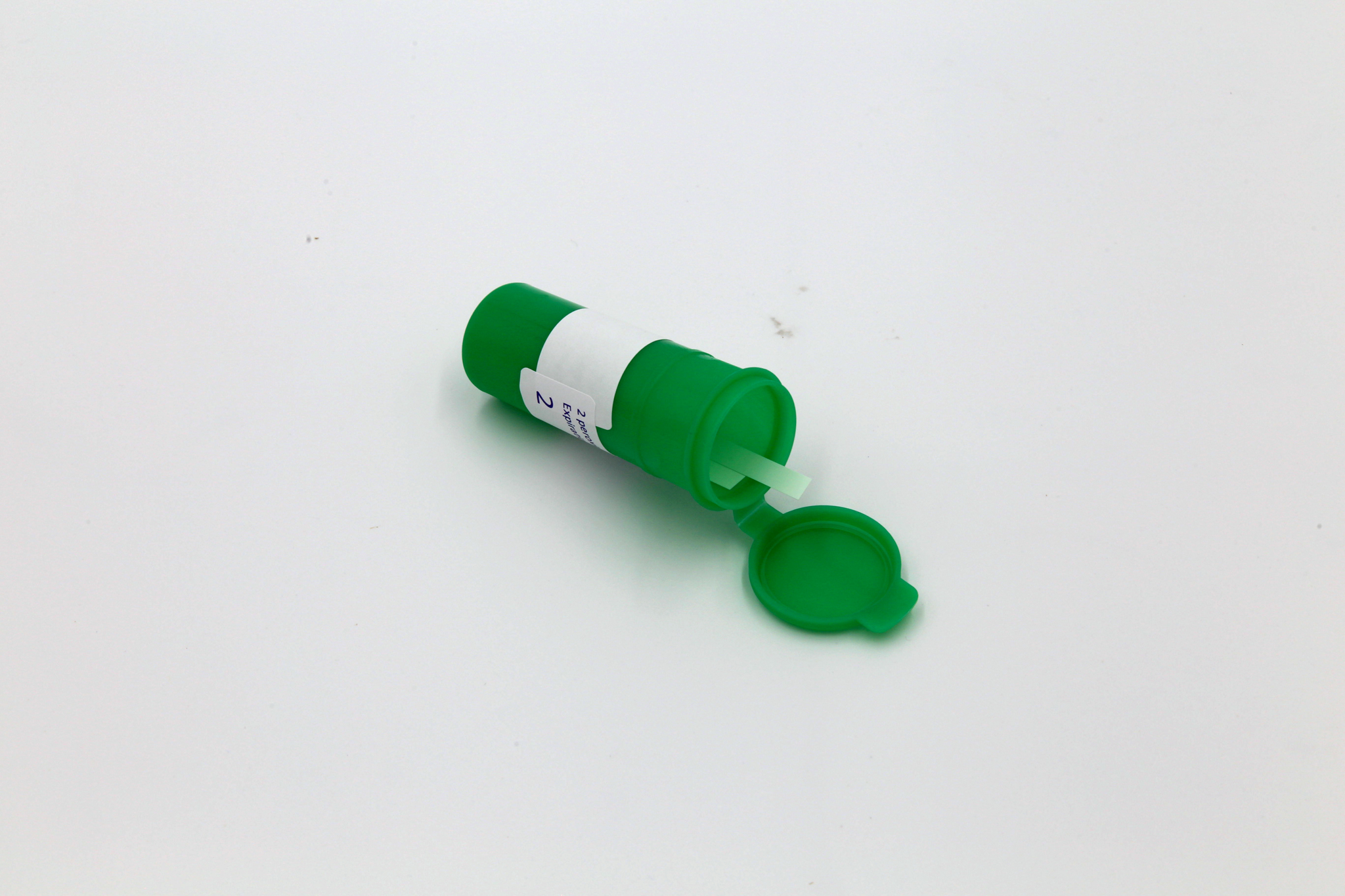 Open green canister with peroxide test strips on a white background